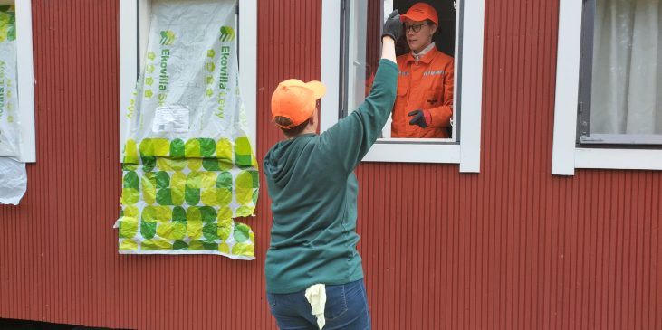 Kaksi naista irrottaa ikkunaa kunnostettavaksi punaisesta rakennuksesta.