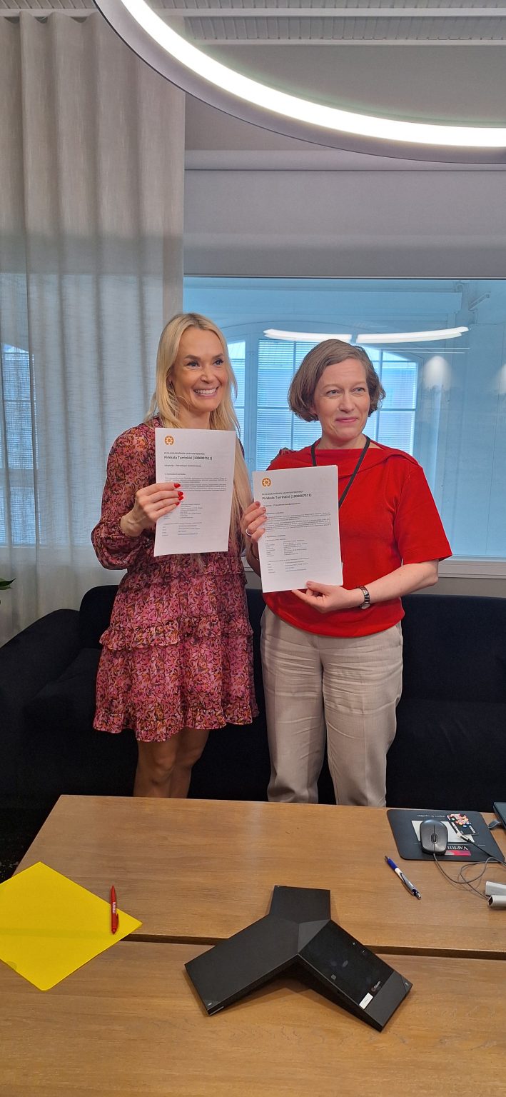 Kaksi henkilöä näyttää käsissään allekirjoitettuja sopimuspapereita.