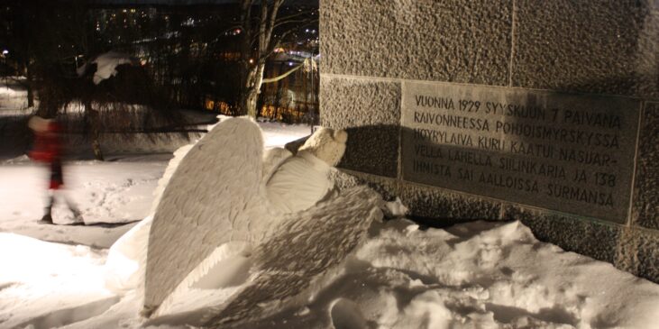 Enkeli pimeässä, lumisessa illassa muistomerkin juurella.